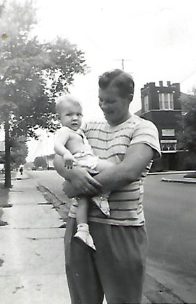 young Bobby held in his father's arms out on the street near their house